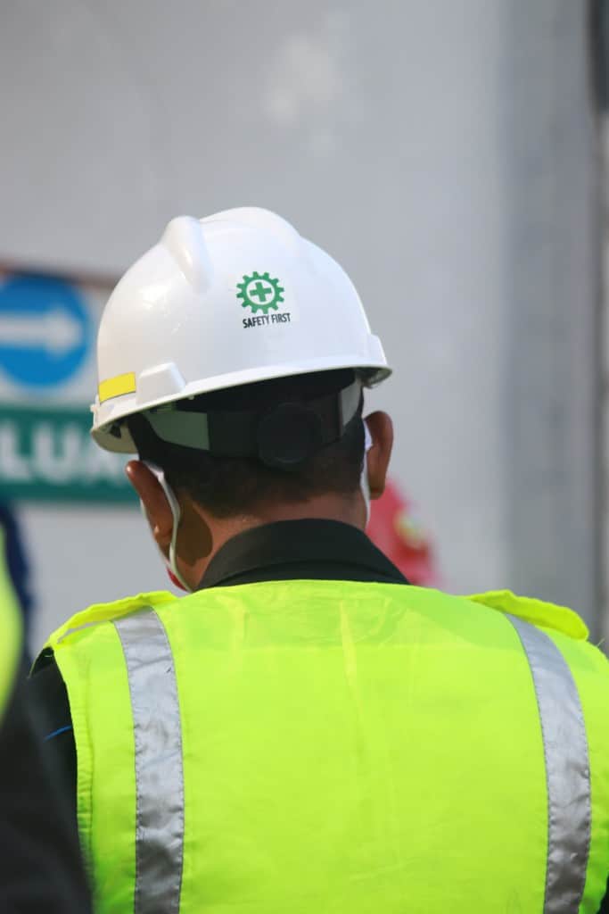 Construction worker wearing a white hard hat labeled