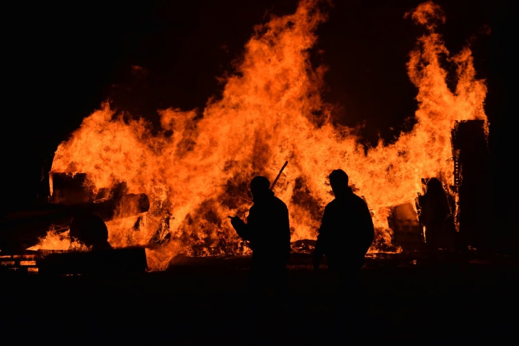 Emergency management in action: Silhouetted responders assess a massive fire, highlighting the urgency of crisis preparedness and disaster response in Hawaii. Stay ahead of emergencies with effective risk management strategies.